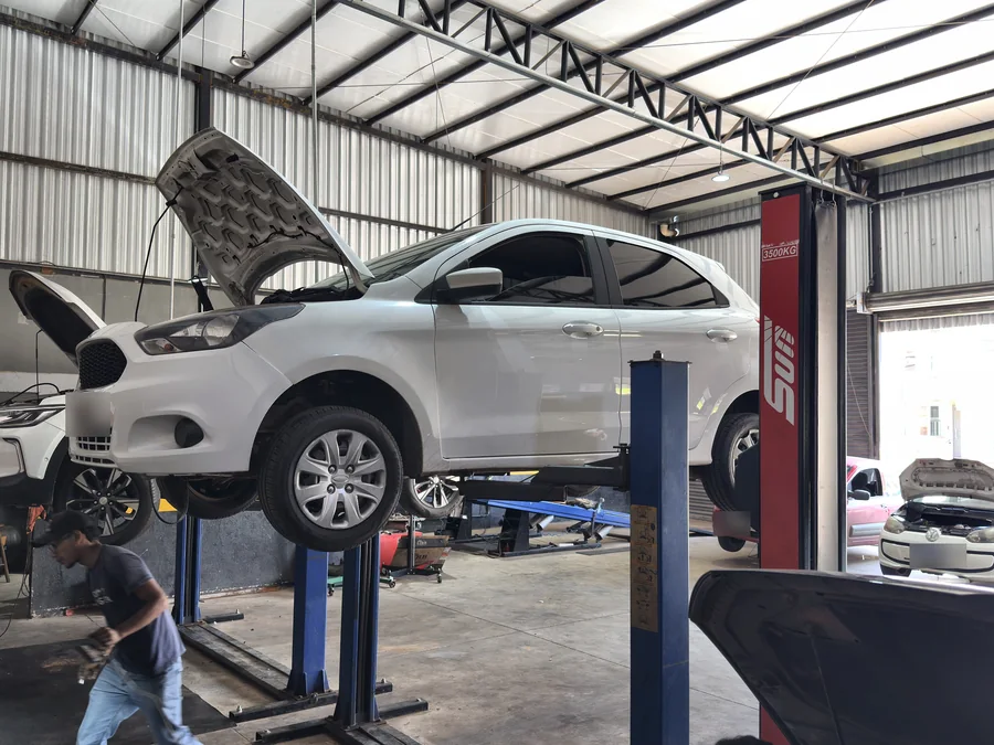 Área de serviço da VP7 com carros nos elevadores, um deles com o capô aberto