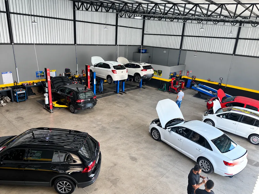 Vista do alto da oficina da VP7, com carros nos elevadores, carros em atendimento com o capô aberto e a equipe trabalhando